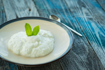 Plate with fresh yogurt on wooden table