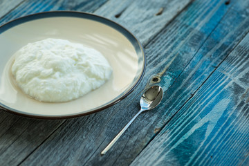 Plate with fresh yogurt on wooden table