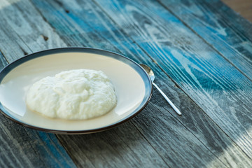 Plate with fresh yogurt on wooden table