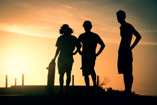 Teen boys silhouette at skate park on summer