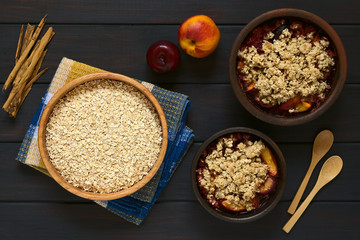 Rolled oats with plum and nectarine crumble, photographed on dark wood with natural light