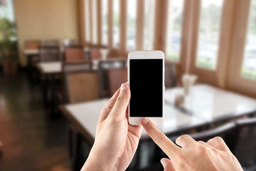 Hand using mobile smartphone in vertical position, blurred backg