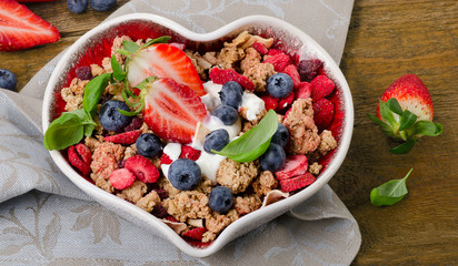 Muesli with fresh berries and yogurt in heart shaped bowl . Heal