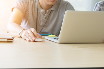 Young man sitting at desk holding mouse and working on computer