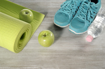 yoga mat with sport shoes and healthy food on a wooden background