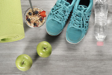 yoga mat with sport shoes and healthy food on a wooden background