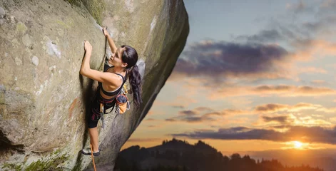 Gordijnen Young attractive female rock climber climbing challenging route on steep rock wall against scenic sunset background. Summer time. Climbing equipment © anatoliy_gleb