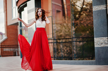 Obraz premium Portrait of fashionable girl at red evening dress posed backgrou