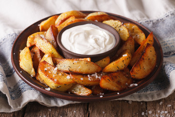 Baked potato wedges with herbs on a plate closeup. Horizontal
