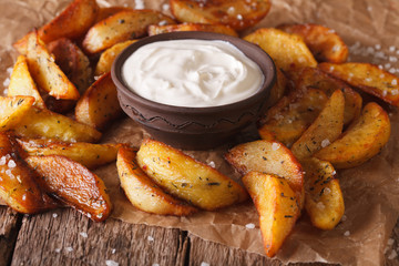 Baked potato wedges and sauce close-up on the table. Horizontal
