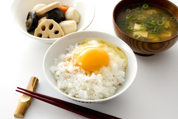 白い背景のみそ汁と醤油のかかったたまごかけごはんと煮物と箸　