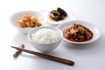 白い背景の3種類のキムチと箸とごはん