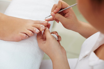 Obraz na płótnie Canvas Woman receiving pedicure by beautician in nail salon