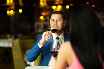 Beautiful young couple with glasses of red wine in luxury restaurant.focus on man