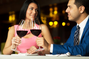 Beautiful young couple with glasses of red wine in luxury restaurant