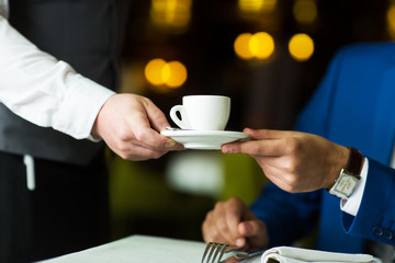 Fototapeta na wymiar close-up of a waiter serves coffee young businessman in a restaurant