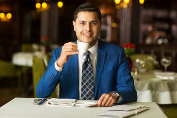 young handsome businessman drinking coffee in a restaurant