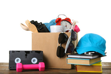cardboard box with things to move on a wooden table isolated on white background