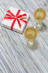 Two glasses of white wine and a gift