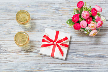 Two glasses of white wine, flowers and a gift