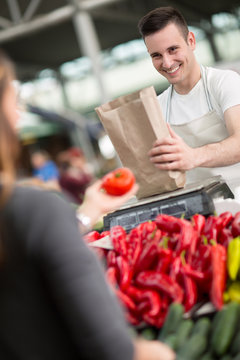 smile salesman measuring vegetables in grocery store.