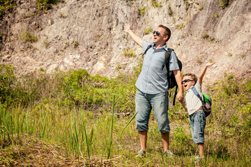 Father and son standing near the pond at the day time.