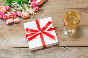 Glass of white wine, flowers and a gift