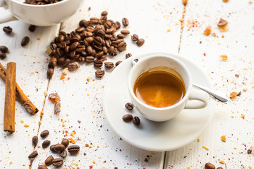 Coffee Cup, Beans, Cinnamon Sticks on White Wooden table
