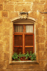 Fototapeta na wymiar High window with flowers on the windowsill in the city of Valletta - the capital city of Malta.