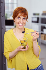 frau isst einen obstsalat am arbeitsplatz