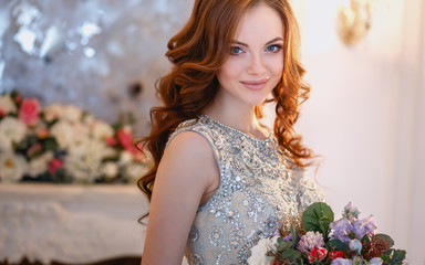 Fototapeta na wymiar Beautiful young lady in a luxury dress in elegant interior with a bouquet of flowers