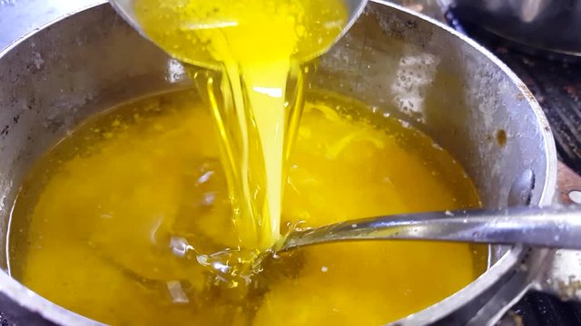 Pouring melted and clarified butter, in a metal casserol 60fps