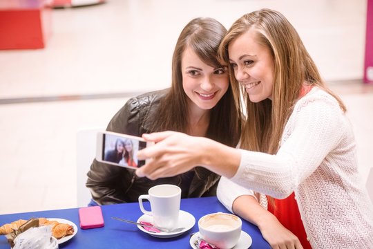 Women taking a selfie on phone while having coffee in mall
