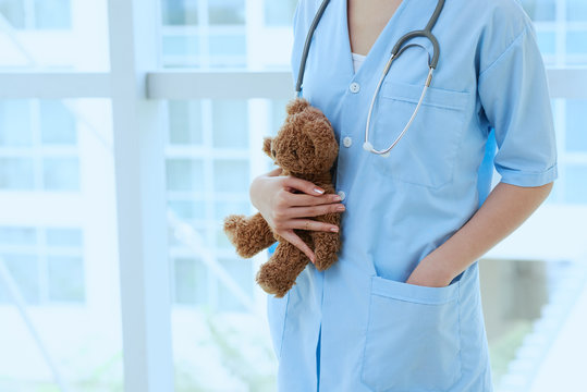 Cropped image of female pediatrician holding little teddy bear