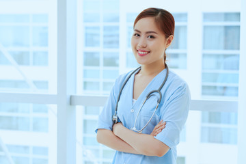 Young confident Vietnamese doctor standing with her arms folded