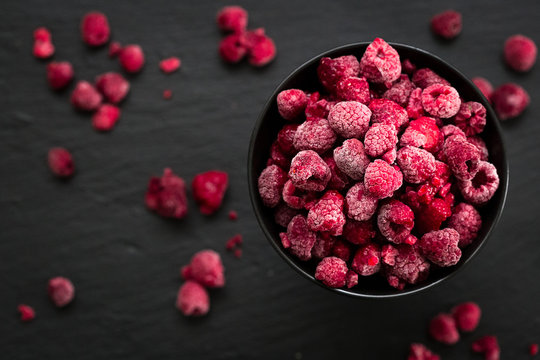 Frozen Raspberries in Bowl, Covered with Ice on Dark Background, Top View