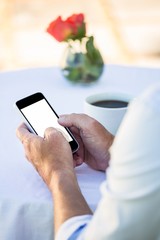Close up of masculine hands using smartphone at a table