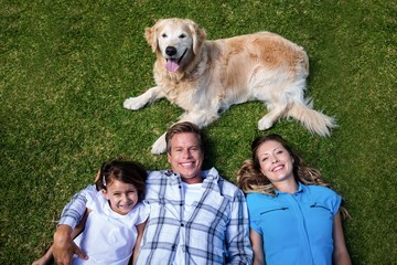 Happy family lying ion grass with their dog