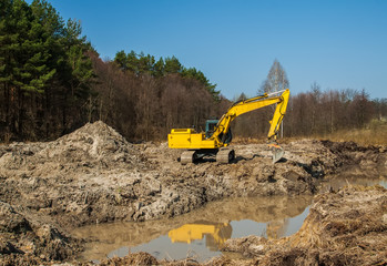 large yellow excavator Yellow on a construction site against blu sky