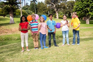Children standing with balloons in the park