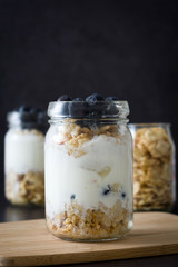 Yogurt with fresh blueberries and cereals on black background
