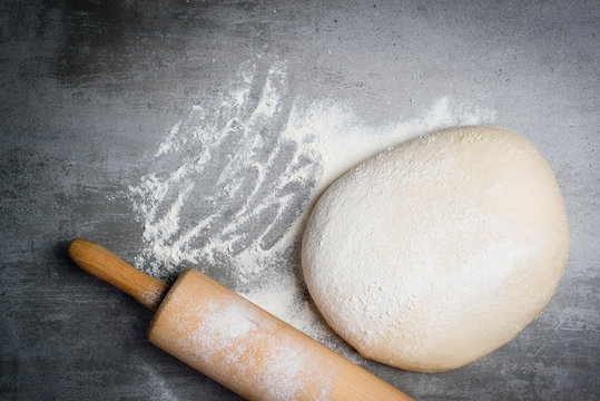 Dough, flour and rolling pin on a stone table
