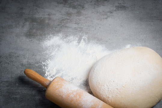 Dough, flour and rolling pin on a stone table