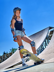 Teen girl rides his skateboard in skatepark outdoor. Skateboarding is extreme sport.