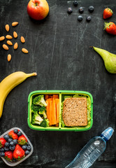 School lunch box with sandwich, vegetables, water and fruits