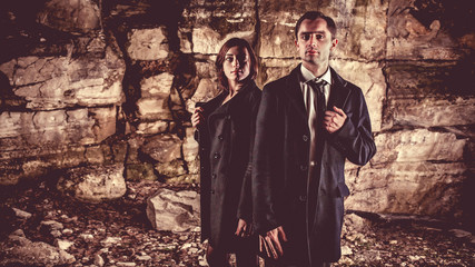 Naklejka premium Couple of well dressed peolpe on the dark rocks background.