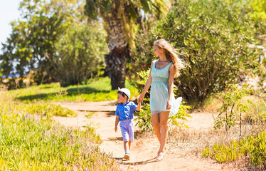 Fototapeta premium Happy mother with child son having fun outdoors in summer day