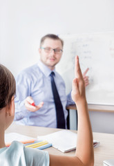 student raising her hand in the classroom