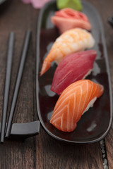 Sushi nigiri set on a black plate over wooden table