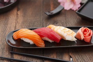 Sushi nigiri set on a black plate over wooden table